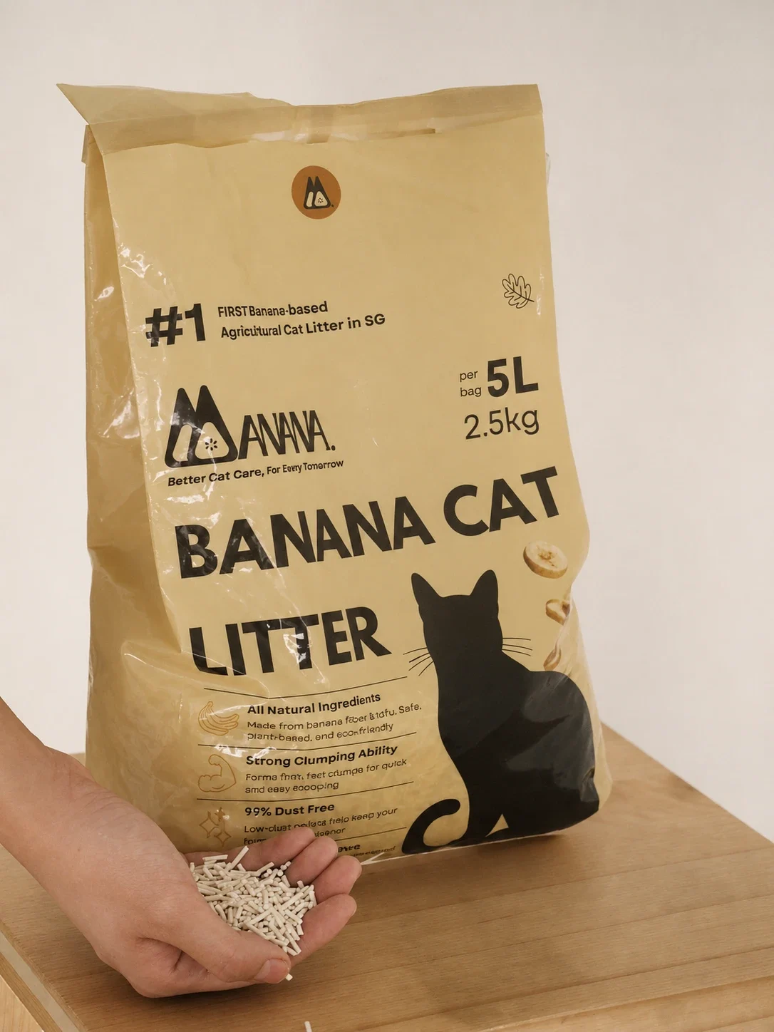 A hand holding plant-based pellets beside the upright MANANA Banana Cat Litter bag